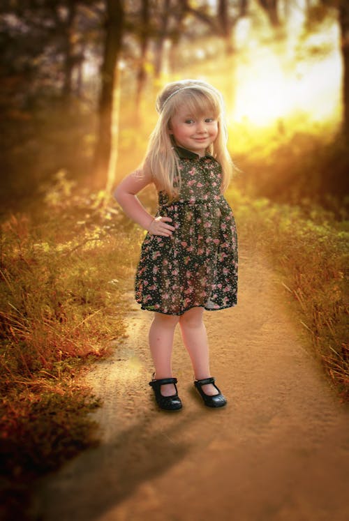 Free Girl in Black and Pink Floral Sleeveless Dress Stands in Pathway Stock Photo