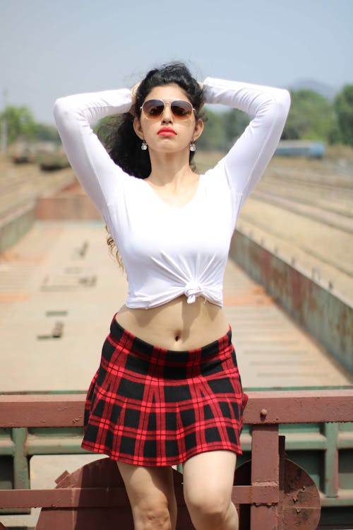 Woman in White Long Sleeve Crop Top and Red and Black Plaid Skirt Wearing Sunglasses