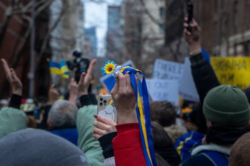 Free Person Holding a Blue and Yellow Ribbon Among a Group of Protesters Stock Photo
