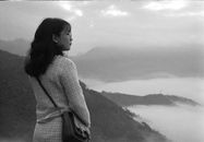 Grayscale Photo of Woman Standing on Mountain