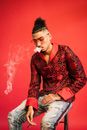 Man in Red and Black Floral Long Sleeved Shirt Smoking
