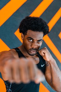 Close-up portrait of a determined male boxer in action, with a striking black and orange background.