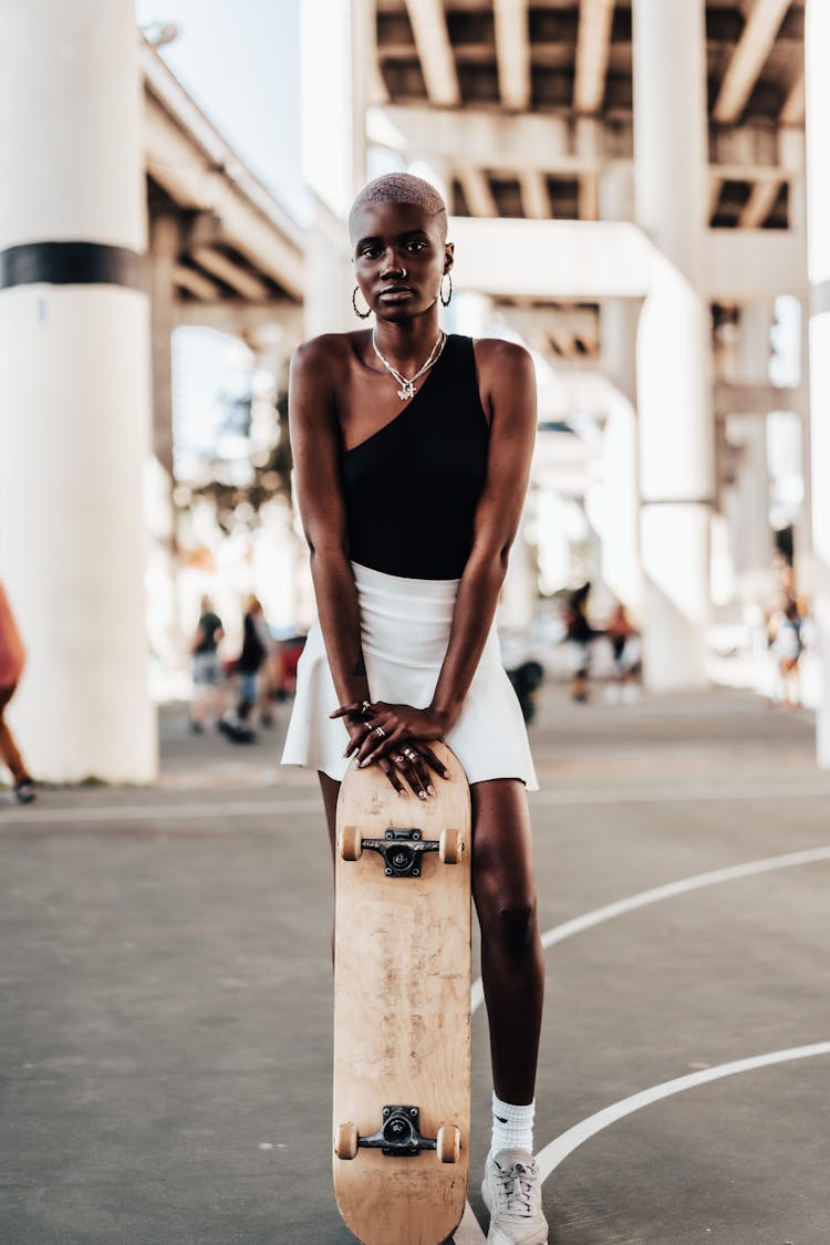 Woman In Tennis Skirt Leaning On Skateboard