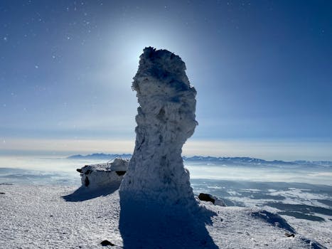 A striking snow-covered rock formation against a clear winter sky in Lipnica Wielka, Poland.