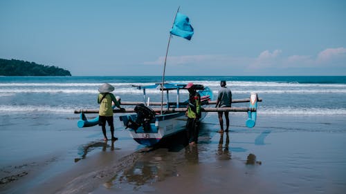 Fishermen Pushing Their Boat in The Sea