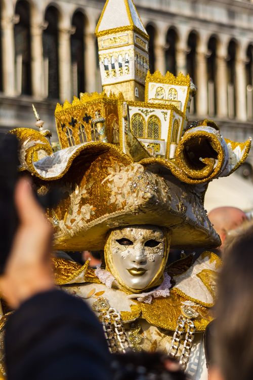 Free Intricate costume and mask at Venice Carnival, featuring golden details and architectural headpiece. Stock Photo