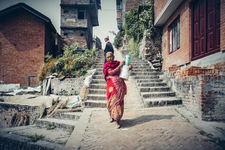 Elderly Woman In Traditional Clothing Carrying Bucket