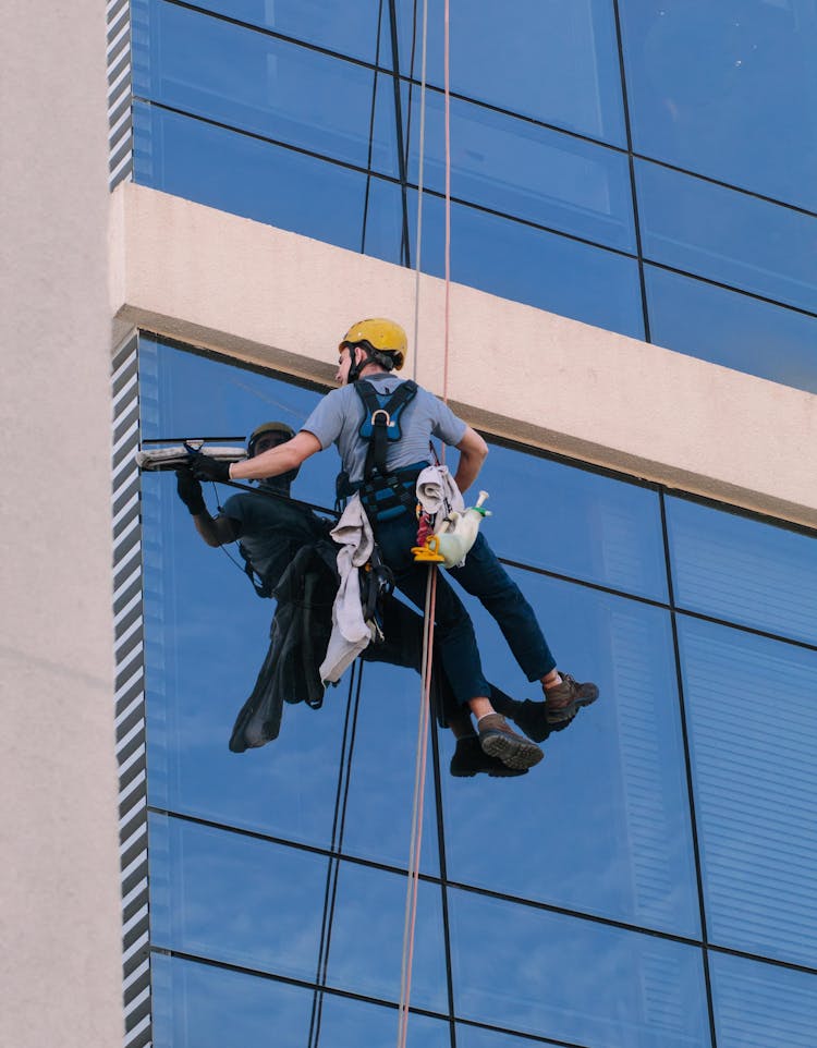 A Man Cleaning Windows Hanging In A Rope