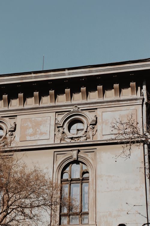 Free Close-up of an old building's faded exterior showcasing classic European architectural elements. Stock Photo