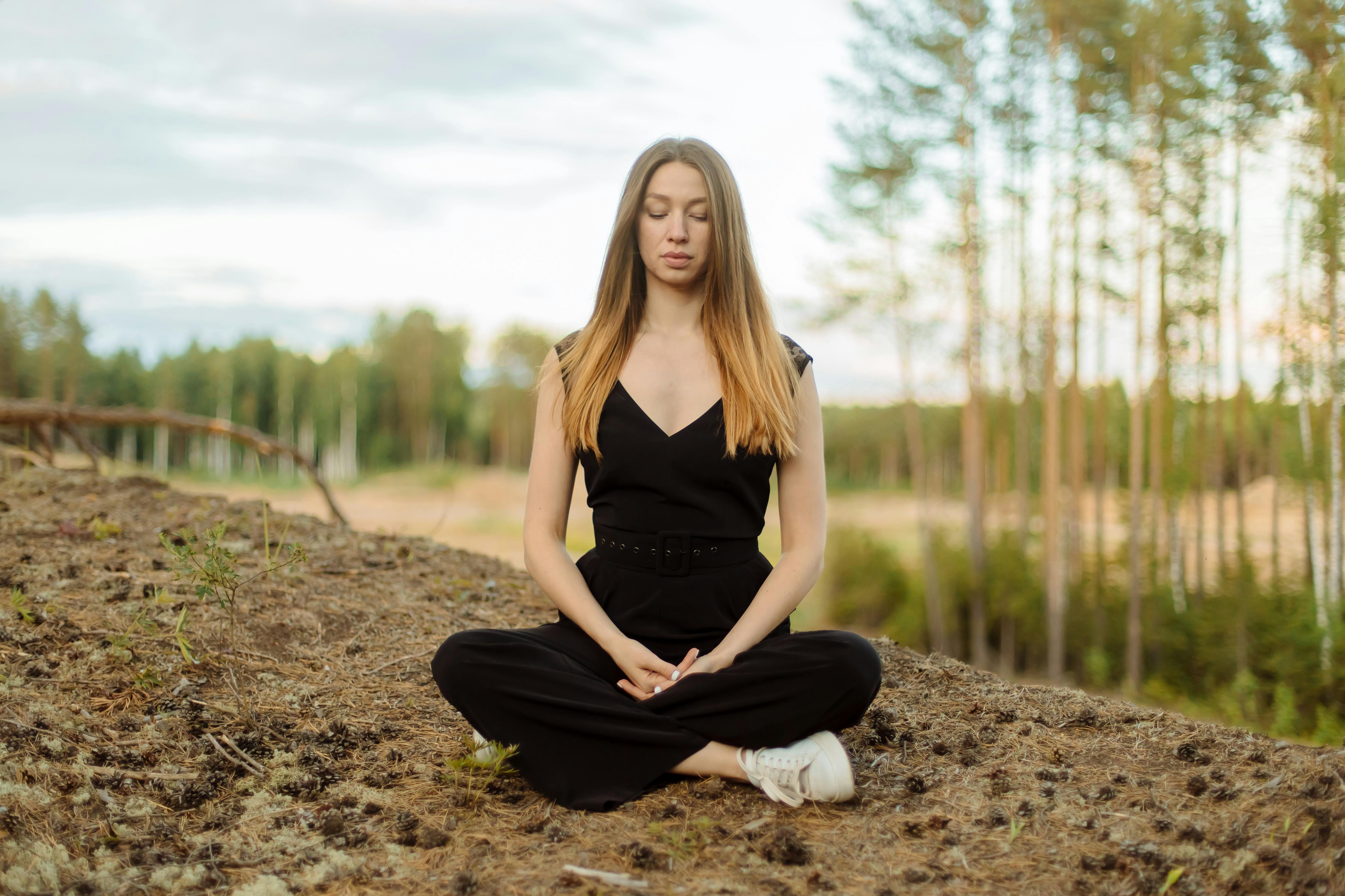 Caucasian woman meditating outdoors, embodying mindfulness and peace in a serene setting.