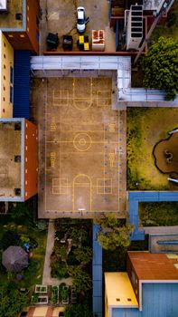 Drone shot capturing a vibrant urban basketball court surrounded by residential buildings.