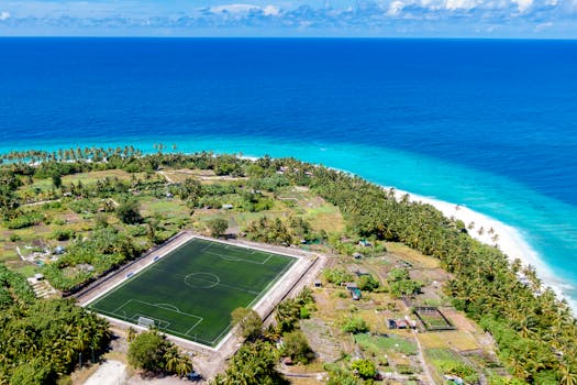 Stunning aerial view of a soccer field on a tropical island by the ocean.