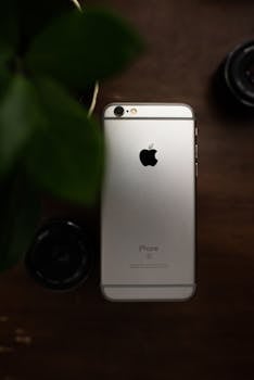 A sleek smartphone lies on a wooden table, captured in a minimalist style.