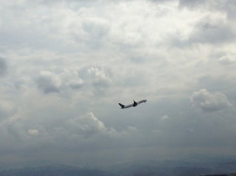 An airplane soars through a dramatic cloudy sky, captured in flight.