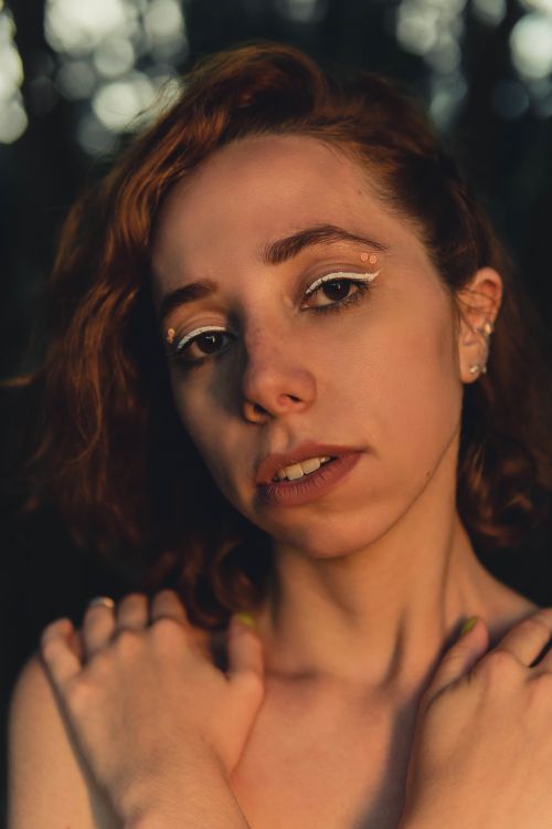 Free Portrait of a woman with creative eye makeup in natural sunlight, showcasing elegance and emotion. Stock Photo