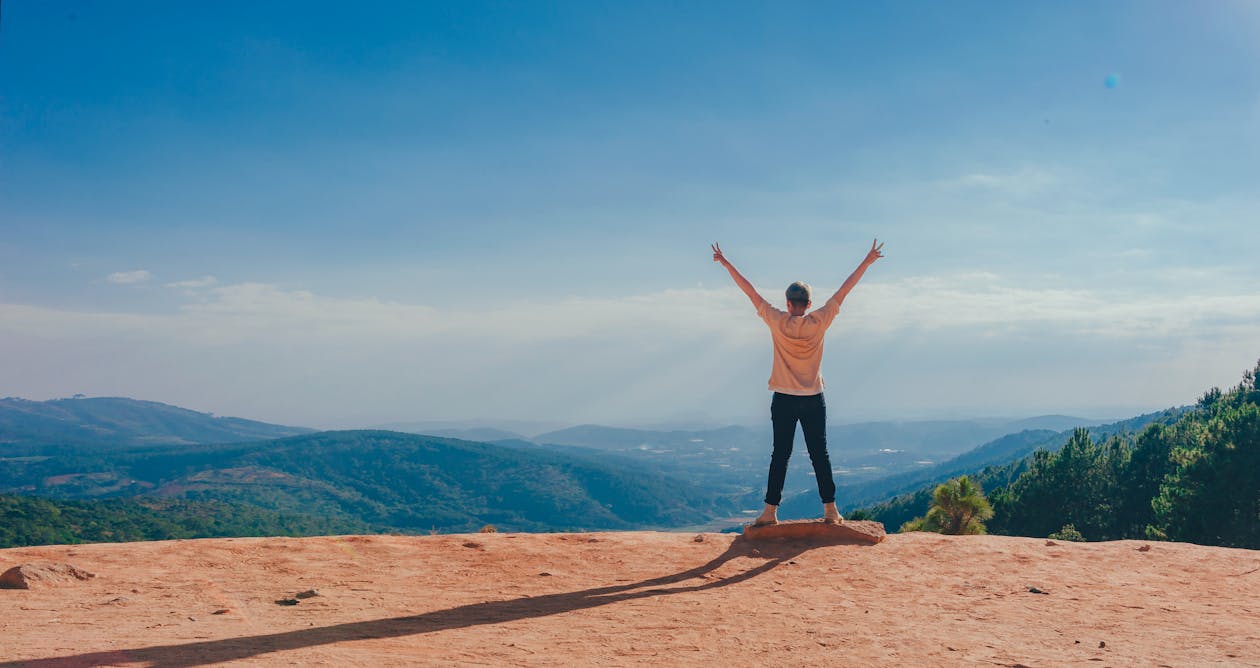 Free Person in Beige Top on Mountain Cliff Stock Photo