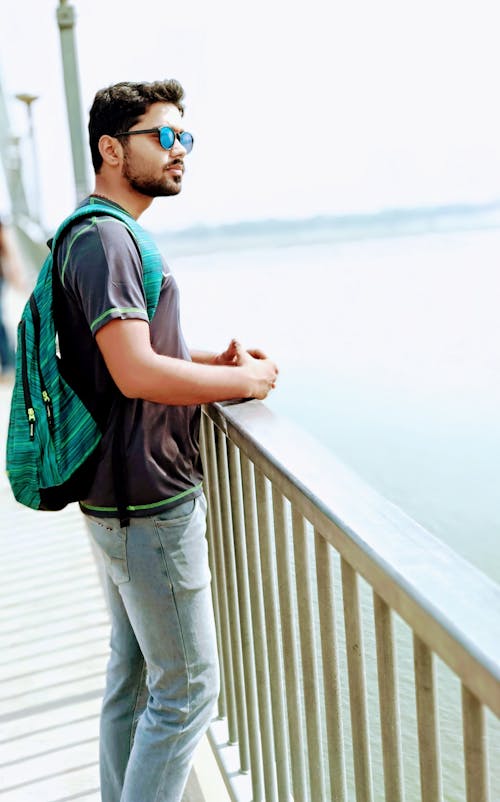 Man Wearing Black Shirt and Blue Denim Jeans Standing on Dock