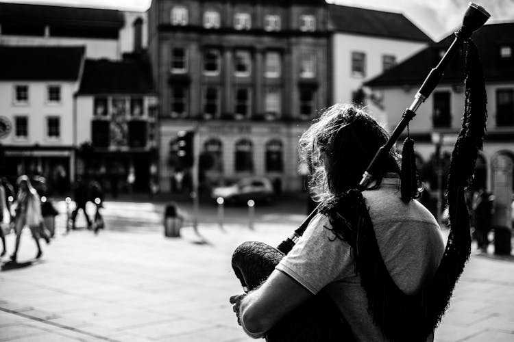 Grayscale Photo Of A Person Holding Bagpipe Instrument