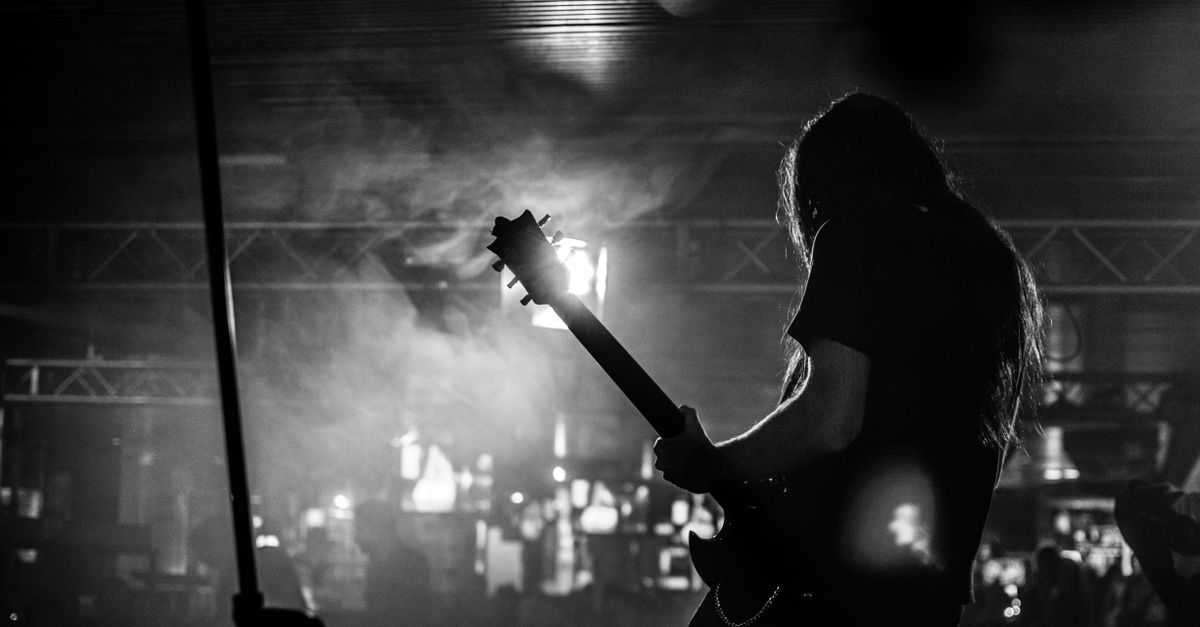 black-and-white photo of a live band playing in a small, dimly lit venue with smoke machines