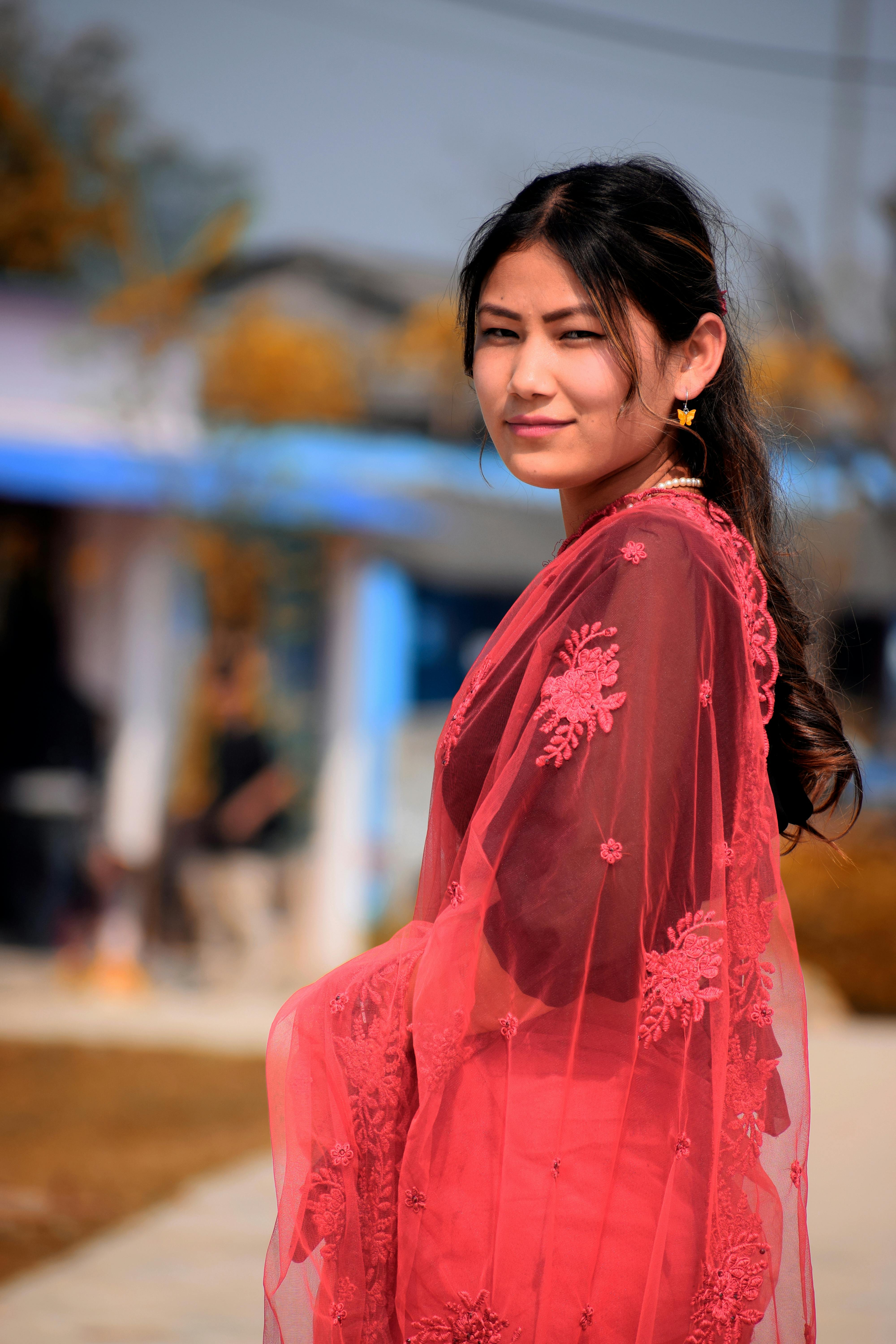 Portrait of a woman in a beautiful red traditional dress standing outdoors on a sunny day.