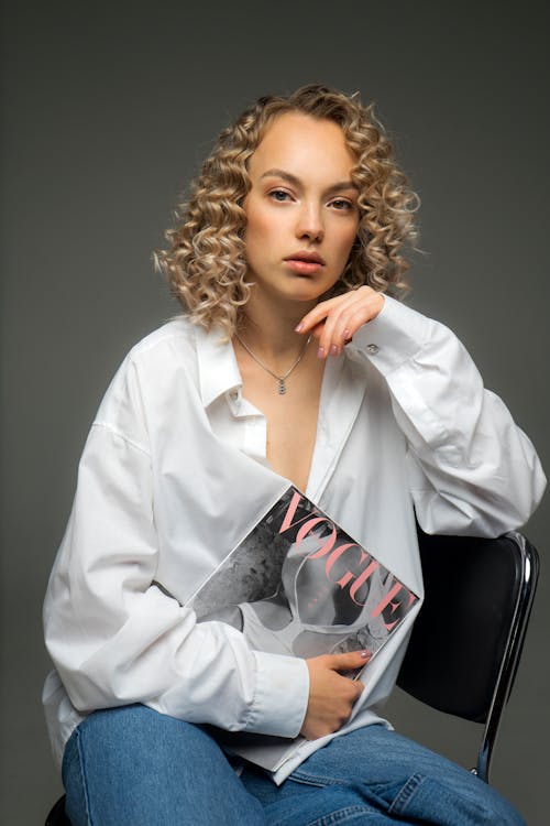 Free Young Woman with Blonde Curly Hair Posing in Studio Sitting on Chair  Stock Photo