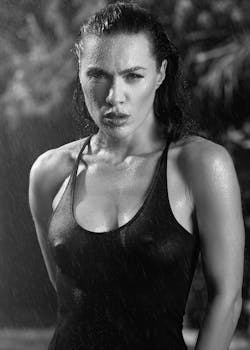 Striking black and white portrait of a young woman in a wet tank top outdoors.