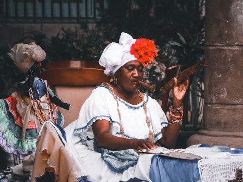 Free Elderly woman in traditional attire and headdress, enjoying a cigar. Stock Photo