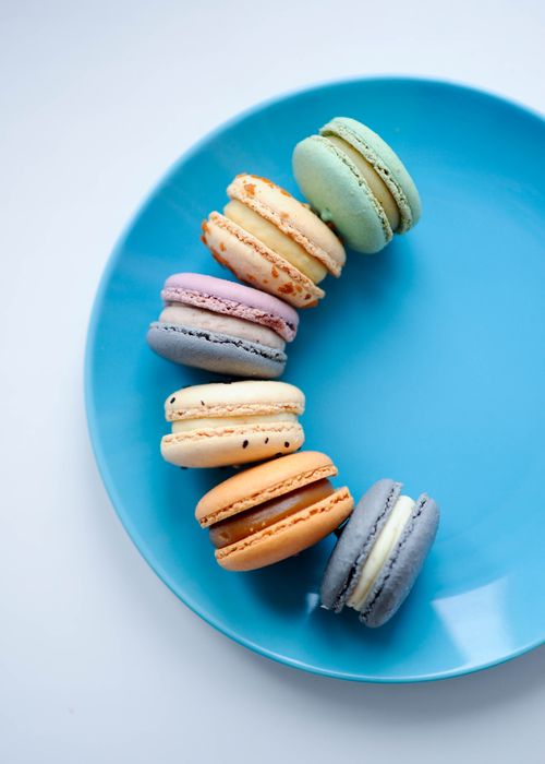 Free A vibrant assortment of macarons displayed on a vivid blue plate, showcasing their colorful variety. Stock Photo