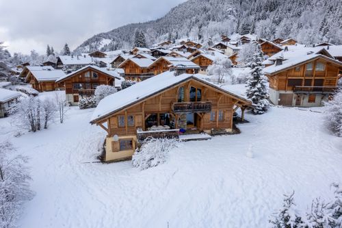 Free Aerial view of snow-covered wooden chalets in Les Contamines-Montjoie, France during winter. Stock Photo