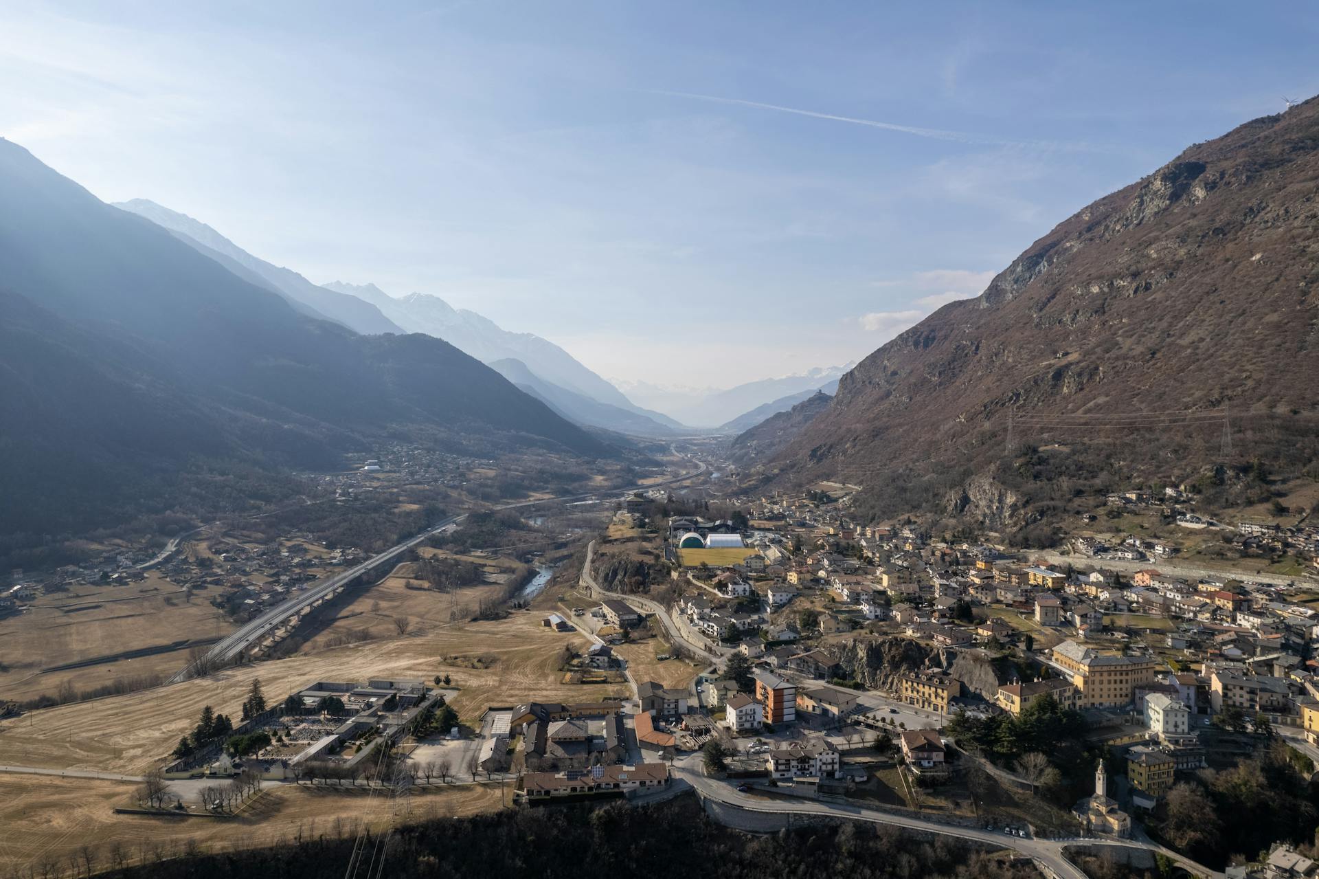 Scenic aerial view of a valley town in Northern Italy surrounded by mountains.