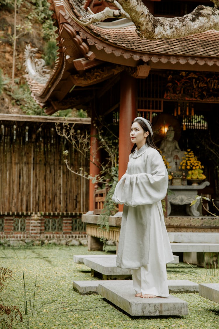 Young Woman Standing Barefoot On Stone Step In Asian Temple Pond Garden