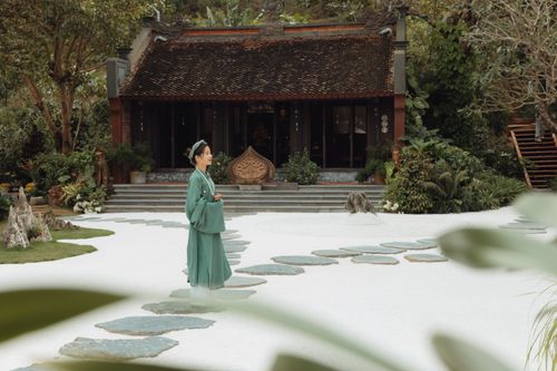 Free A woman in traditional clothing stands serenely in a zen garden near an Asian temple. Stock Photo