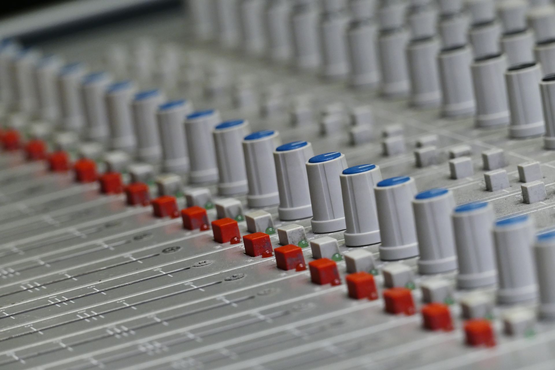Close-up of an audio control panel featuring knobs and sliders for sound mixing.