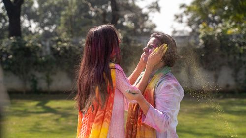 Free A cheerful couple enjoying the vibrant Holi festival, applying colorful powder outdoors. Stock Photo