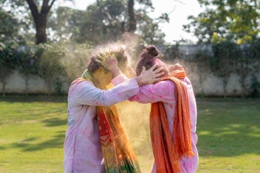 Two people celebrating Holi with colorful powders outdoors, embracing festive spirit.