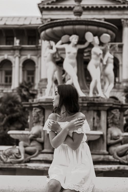 A Grayscale Photo of a Woman in White Off Shoulder Dress Looking Over Shoulder