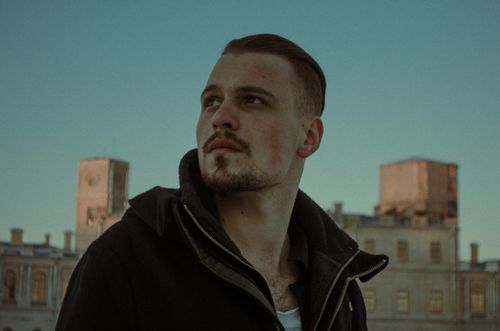 Free Pensive young man outdoors with urban architecture backdrop during daytime. Stock Photo