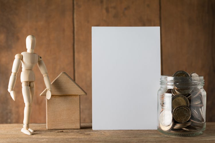 Blank Paper, Jar With Money And A Wooden Figurine 