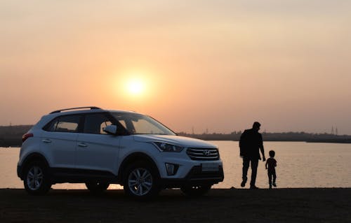 Schattenbild Des Mannes Und Des Kindes Nahe Weißem Hyundai Tucson Suv Während Der Goldenen Stunde