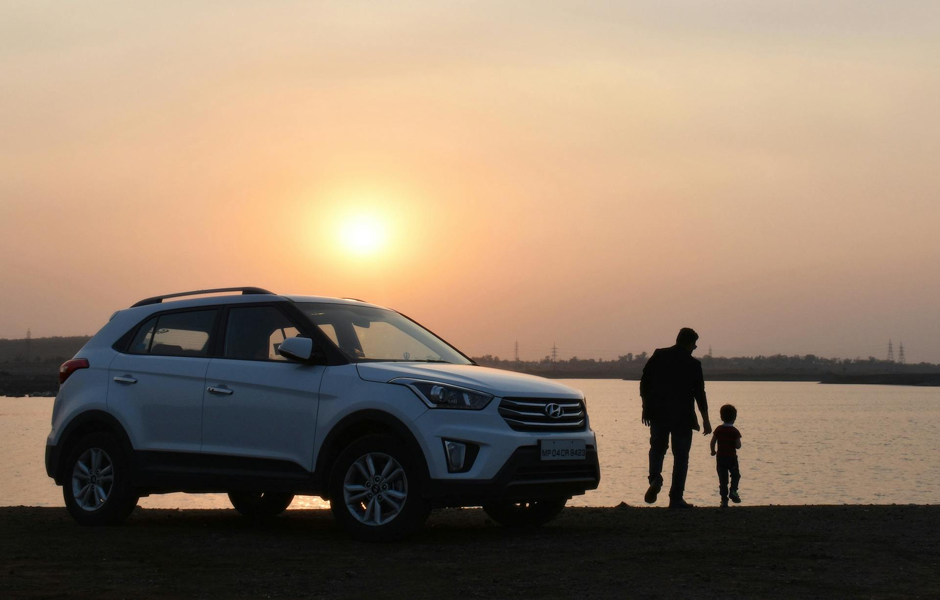 Free Silhouette of Man and Child Near White Hyundai Tucson Suv during Golden Hour Stock Photo