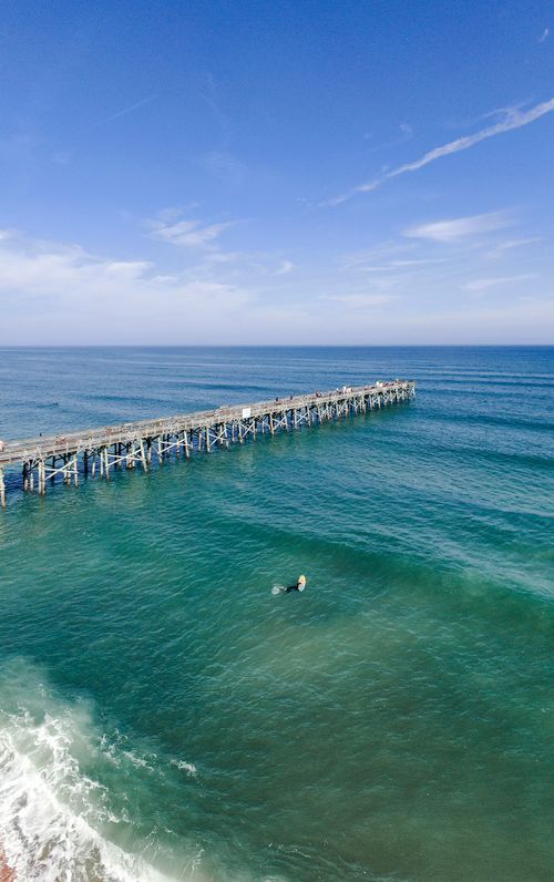 Free Aerial view of Flagler Beach Pier, FL with vibrant ocean scenery and clear blue skies. Stock Photo