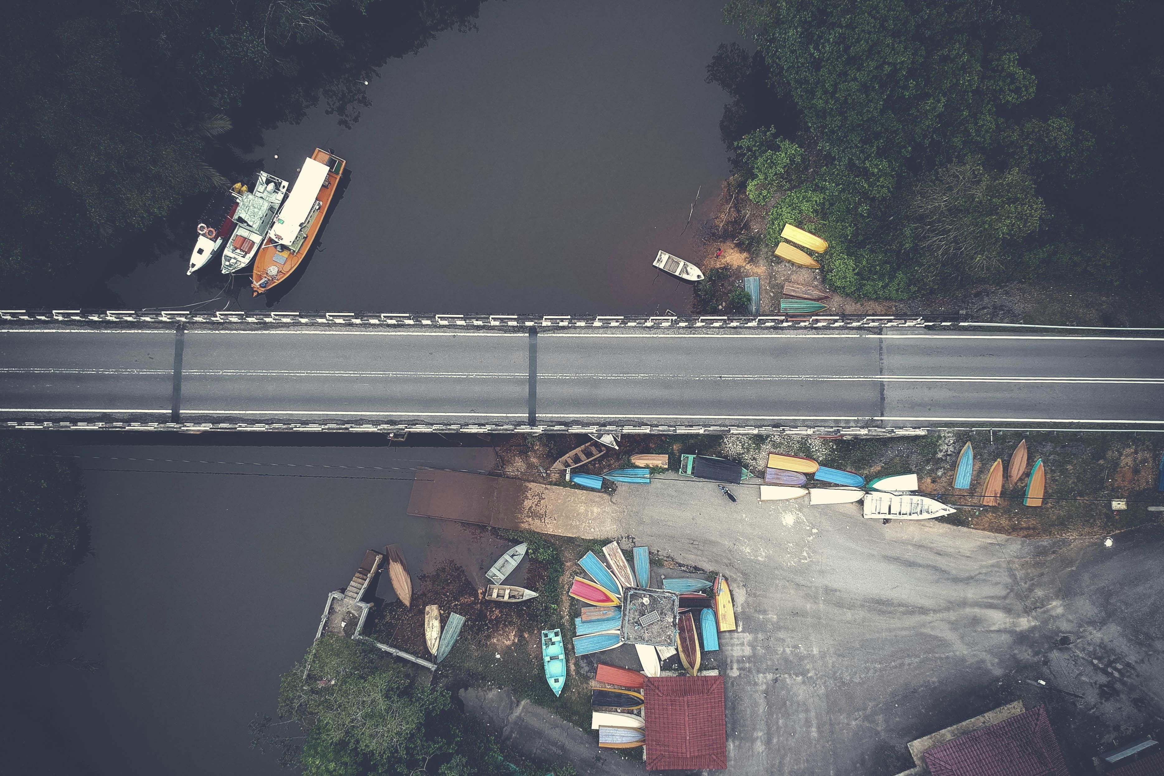 Aerial view of a bridge over a river with boats and greenery, showcasing a blend of nature and infrastructure.