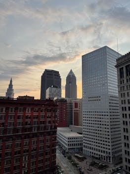 A city's skyline featuring modern skyscrapers against a sunset backdrop.
