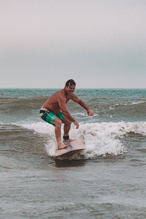 A Shirtless Man Surfing on the Beach