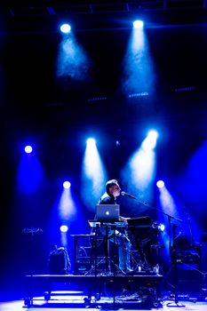 Dynamic live performance featuring a musician playing keyboard on stage under vibrant lighting.