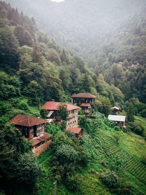 Free Aerial view of rustic homes nestled in lush green countryside with mountains in the background. Stock Photo