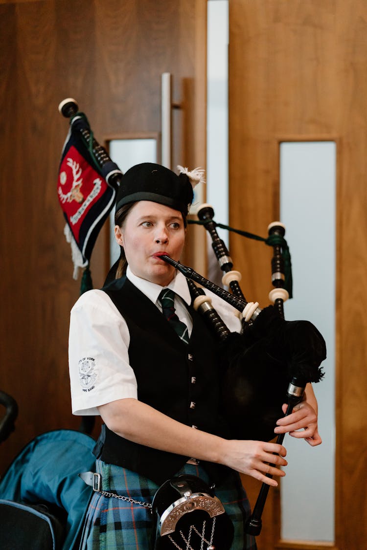 Female Piper In National Scottish Outfit Playing Bagpipes