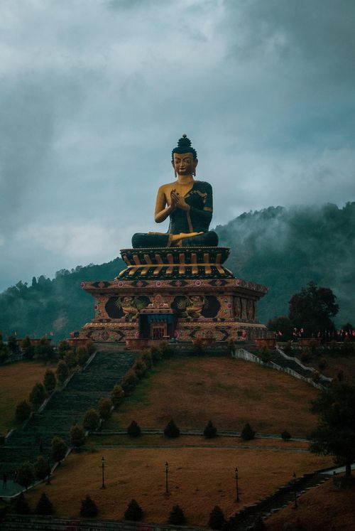Free A stunning view of the giant Buddha statue atop a hill at Tathagata Tsal, Namchi, India, enveloped by mist and greenery. Stock Photo