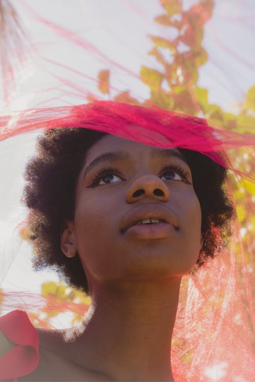 A Low Angle Shot of a Woman Looking Up with Pink Veil on Her Head