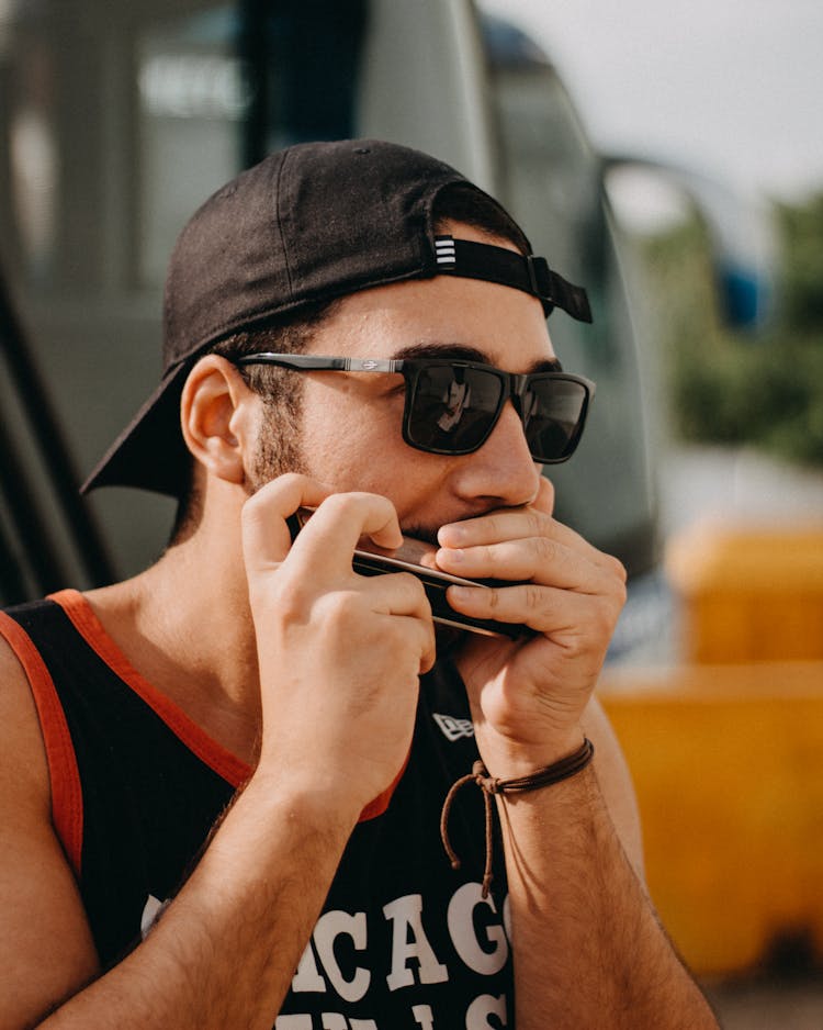 Man In Black Tank Top Playing A Harmonica